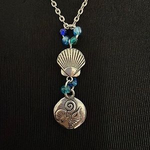 Seashells in silver tone and blue beads on a 20” chain. Nice handmade gift!